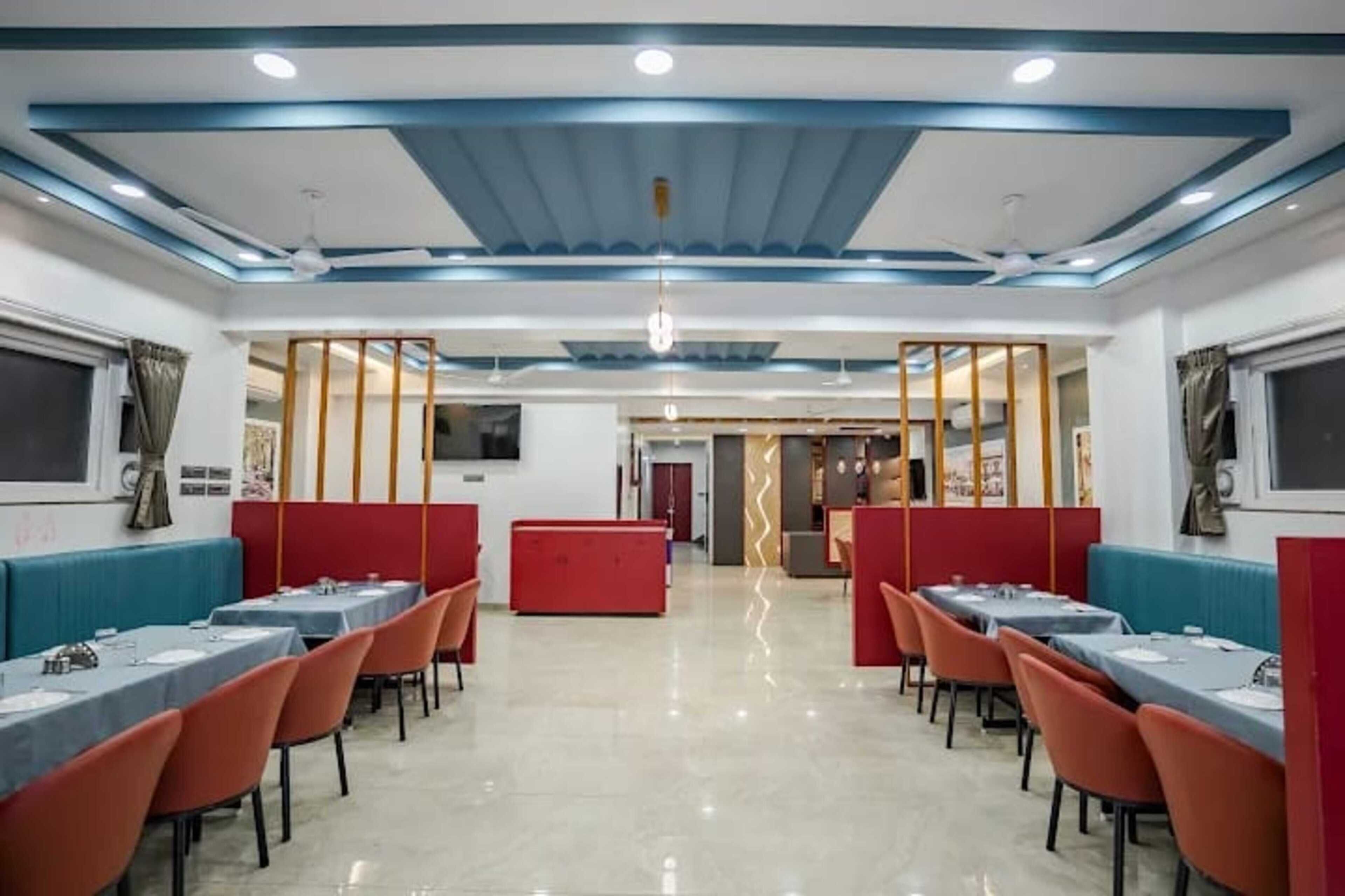 A restaurant with booths and tables, a tiled floor, and a modern ceiling design.