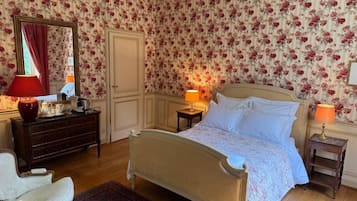 A bedroom with a bed, two bedside tables, a dresser, a chair, and a mirror.