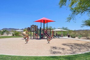 Ein Spielplatz mit Rutsche, Klettergerüsten und einem roten Sonnenschirm.