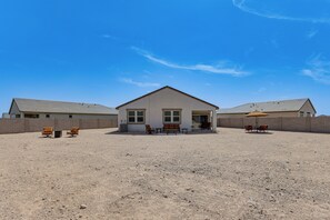 A two-story building with a flat roof, a front porch with a bench, and a patio area with outdoor furniture. - Superstition Mtn Views: Seasonal Golf Getaway (Gold Canyon)