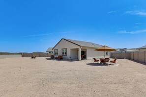 A single-story house with a covered patio area, outdoor seating, and a view of the surrounding landscape. - Superstition Mtn Views: Seasonal Golf Getaway (Gold Canyon)