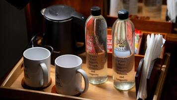 Una bandeja con dos tazas blancas, dos botellas de agua y una olla negra.