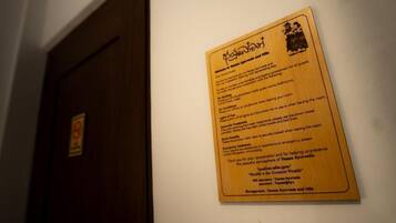 Uma placa de madeira com texto e um logótipo, fixada numa parede num corredor.