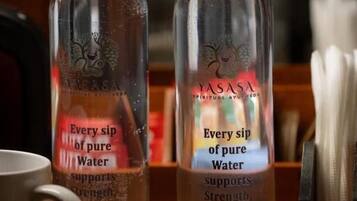 Dos botellas de vidrio transparente etiquetadas 'YASASA' con texto que promociona beneficios para la salud.