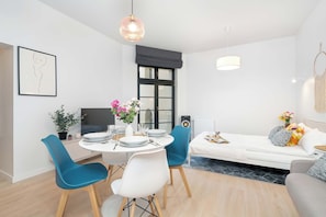 Ein modernes Wohnzimmer mit Essbereich, einer Couch und einem Fernseher.