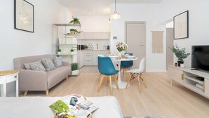 Un apartamento moderno con sala de estar, comedor, kitchenette y televisor.