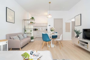 Eine moderne Wohnung mit Wohnzimmer, Essbereich, Küchenzeile und Fernseher.