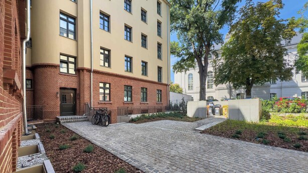 Un edificio con fachada de ladrillo y un patio empavedado con un aparcamiento para bicicletas.