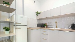 Una cocina moderna con armarios blancos, microondas integrado, cafetera y un lavamanos con grifo dorado.