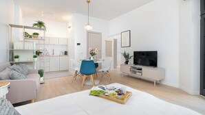 Una sala moderna con un sofá, una mesa de comedor con sillas, un televisor y una estantería.