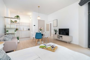 Ein modernes Wohnzimmer mit einer Couch, einem Esstisch mit Stühlen, einem Fernseher und einem Bücherregal.