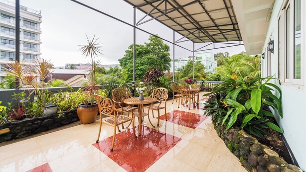Un espace extérieur aménagé en terrasse, doté d’un coin salon abrité, de plantes en pot et offrant une vue sur le paysage urbain.