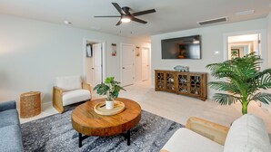 A modern living room with a round wooden coffee table, a sofa, a chair, a television, and a ceiling fan. - May River Fun! Home 9 Mi to Hilton Head Island (Bluffton)