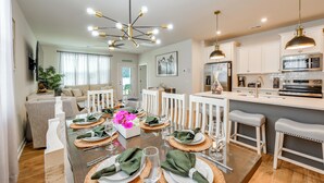 A modern kitchen with stainless steel appliances, a dining area with a glass table set for six, and a living room with a sofa and a plant. - May River Fun! Home 9 Mi to Hilton Head Island (Bluffton)