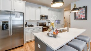 A modern kitchen with white cabinetry, stainless steel appliances, and a central island with seating. - May River Fun! Home 9 Mi to Hilton Head Island (Bluffton)