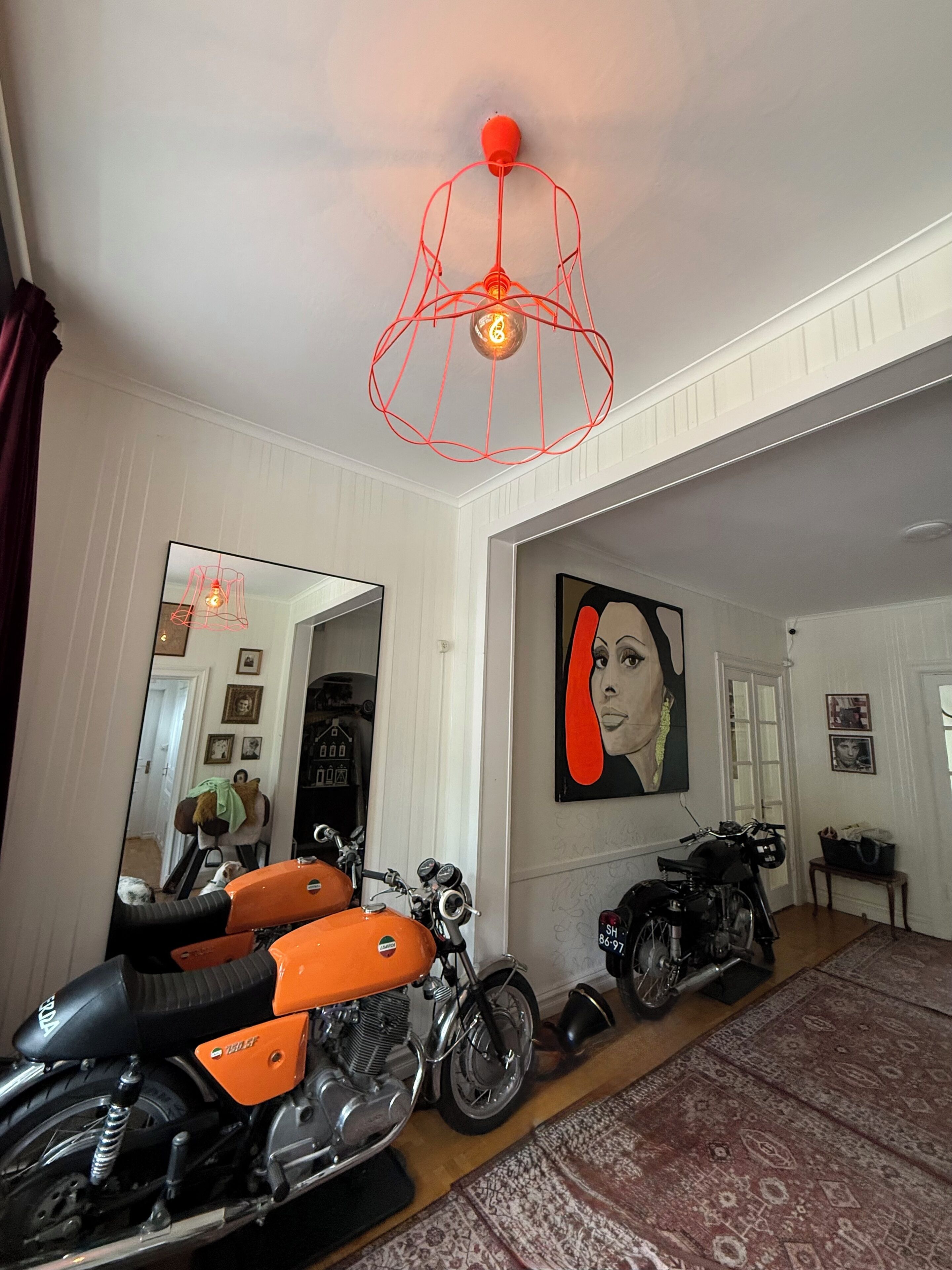Quarto com uma motocicleta, um espelho grande e um quadro na parede.