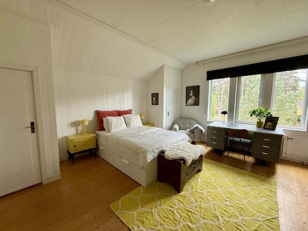 Une chambre à coucher avec un lit, des tables de chevet, un bureau et une fenêtre.