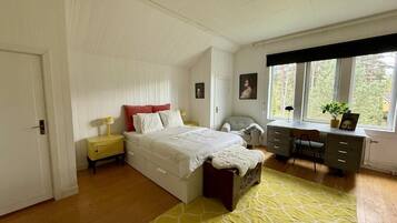 Une chambre à coucher avec un lit, des tables de chevet, un bureau et une fenêtre.