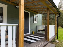 A wooden porch with a black and white striped mat leading to a door.