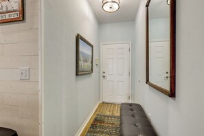 A hallway with a white door, a framed picture on the wall, and a large mirror.