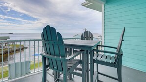 En balkon med et bord og stole, der giver udsigt over vand og en fjer beliggende kystlinje.