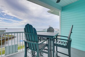 Ein Balkon mit Tisch und Stühlen, der auf ein Gewässer und eine ferne Küste blickt.