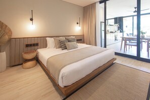 A modern bedroom with a large bed, bedside lamps, a wooden bedside table, and a view of the balcony. - East 88 Unit 4 (Canggu)
