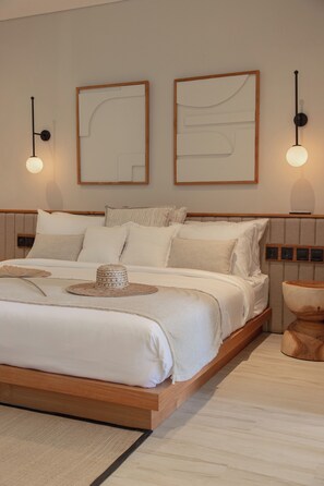 A modern bedroom with a large bed, two wall-mounted light fixtures, and abstract wall art. - East 88 Unit 4 (Canggu)
