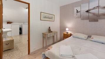 A bedroom with a bed, bedside table, lamp, and a painting on the wall.