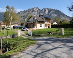 Een tweelaags huis met een balkon, een oprit en een berg op de achtergrond.