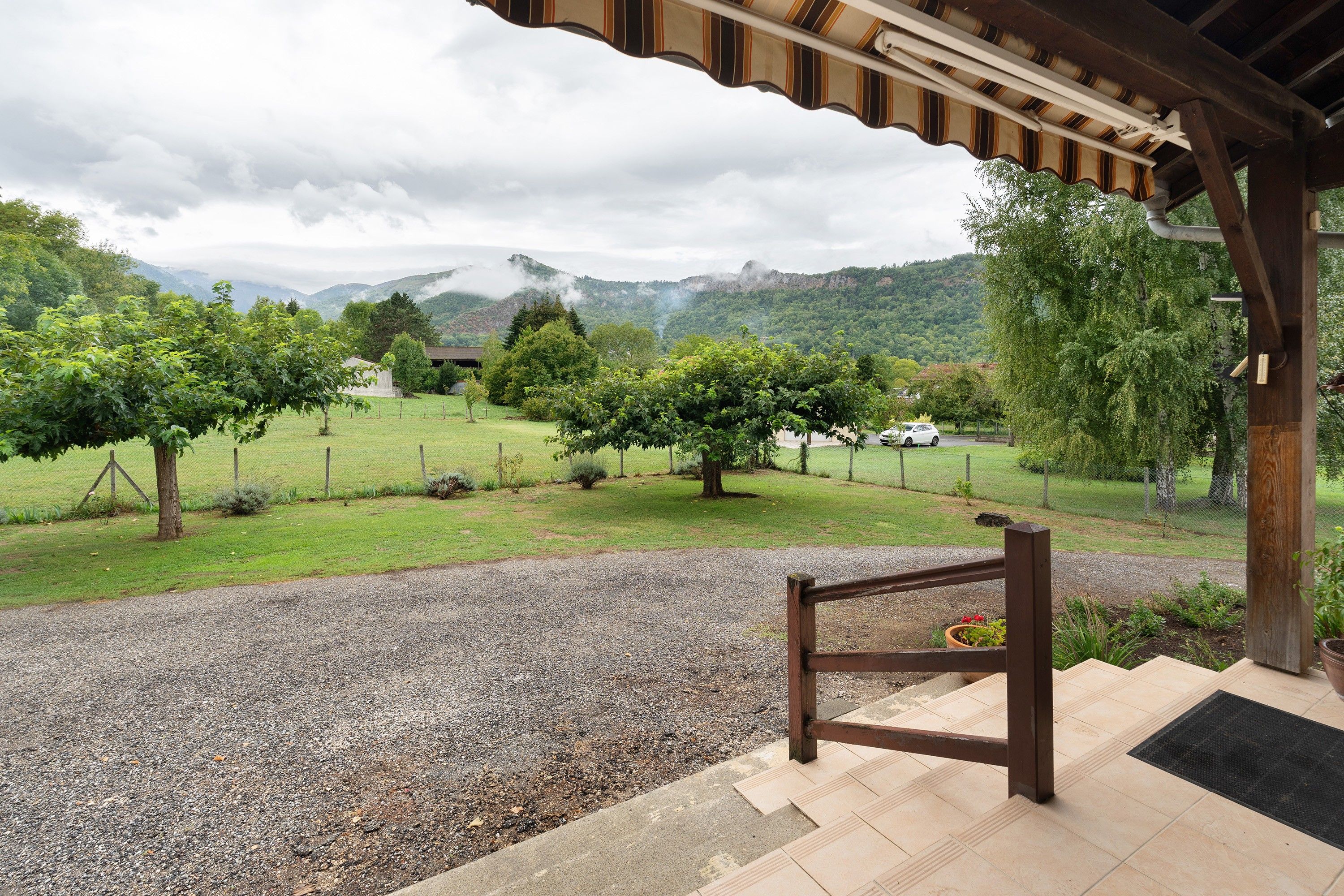 A covered outdoor area with a gravel path leading to a wooden deck.
