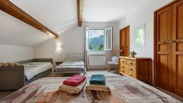 A bedroom with a bed, a dresser, a chair, and a window with a view of mountains.