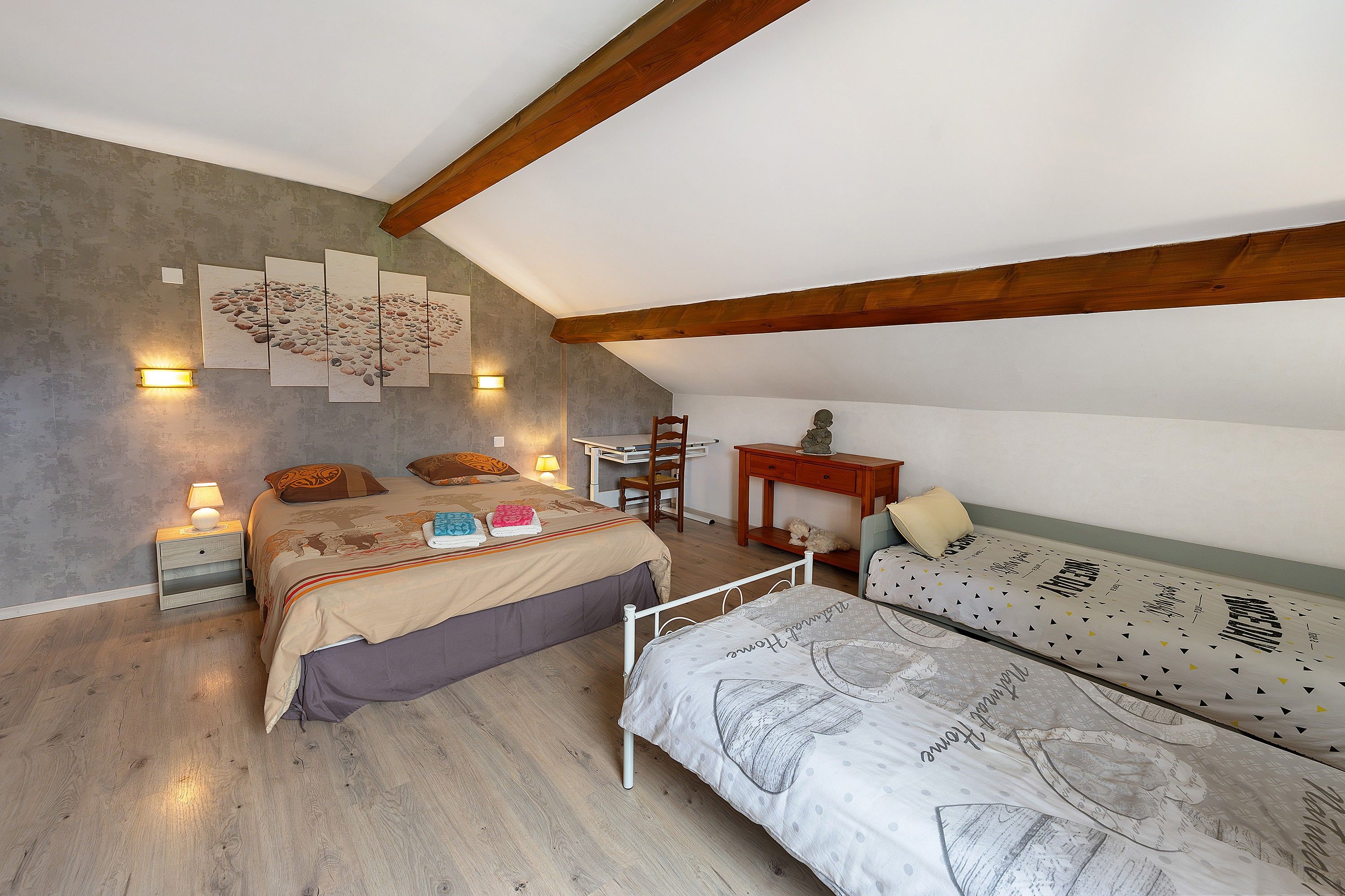 Une chambre à coucher avec un lit, un bureau et un canapé. Il y a des lampes fixées au mur et un tableau accroché au mur.