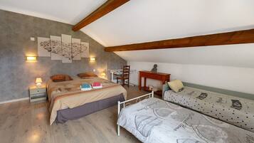 Une chambre à coucher avec un lit, un bureau et un canapé. Il y a des lampes fixées au mur et un tableau accroché au mur.