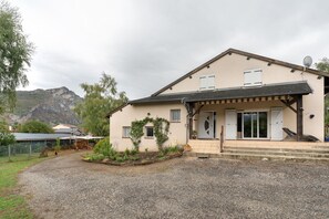A two-story house with a covered porch, a satellite dish, and a mountain in the background.