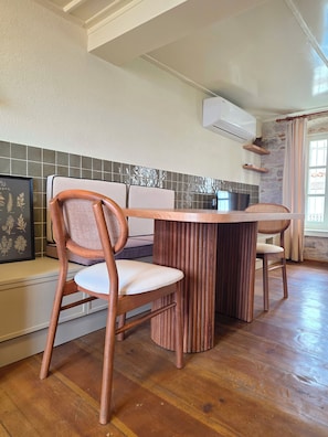 A dining area with a wooden table and chairs, a tiled backsplash, and a stone wall.