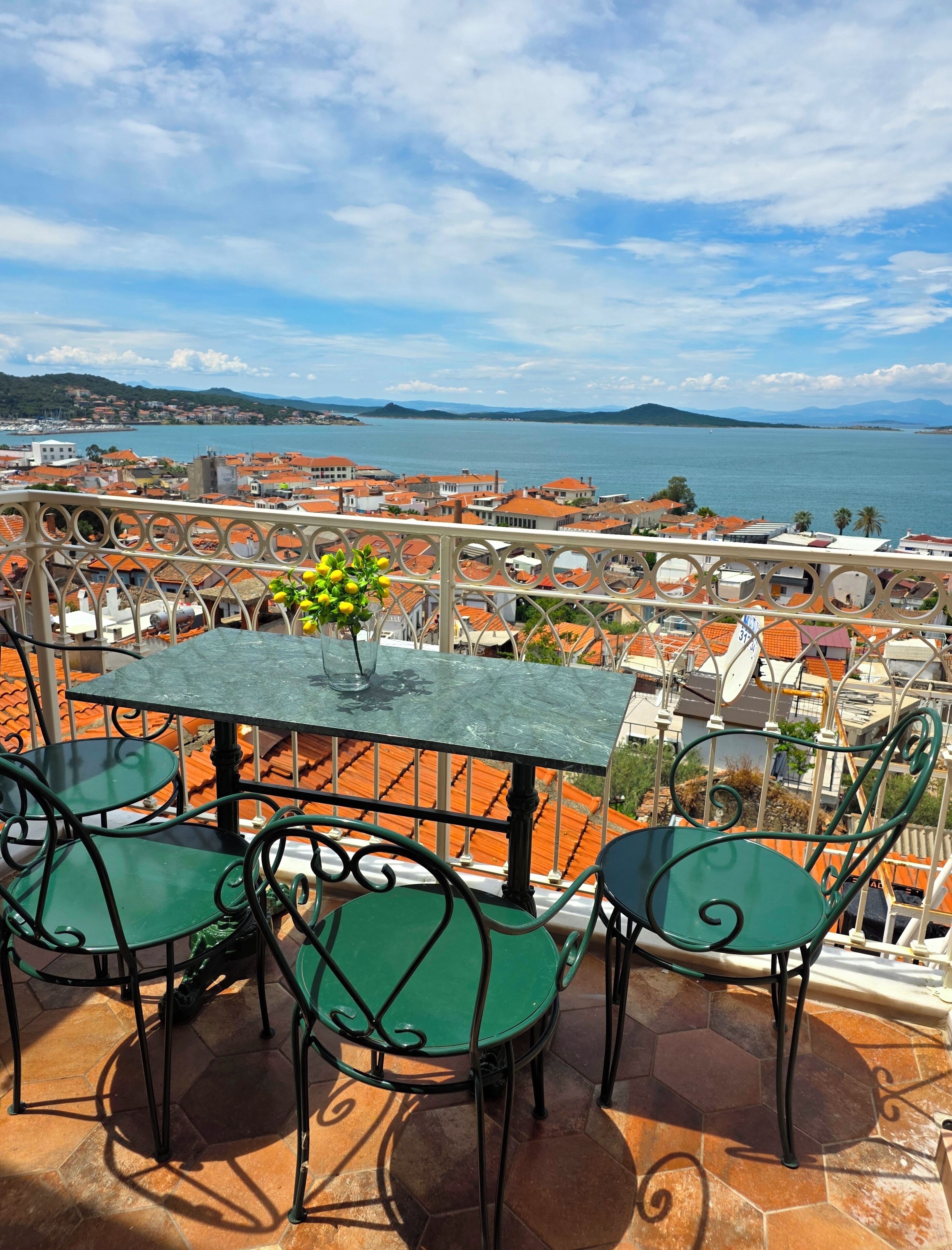 Une terrasse avec une table et des chaises donnant sur une ville côtière.