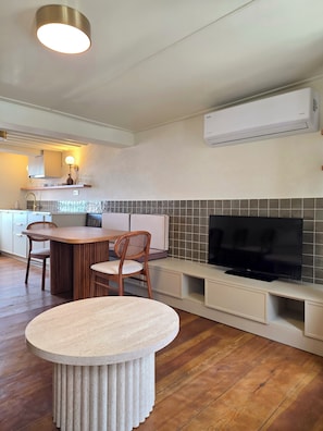 A modern kitchen with a dining area, a flat-screen TV, and a built-in air conditioning unit. - Historic Greek House with Sea View in Ayvalik (Balıkesir)