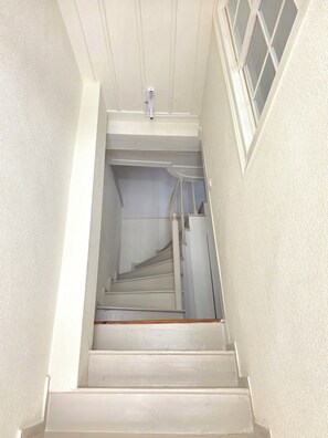 A staircase with a handrail, a light switch, and a window with a grid pattern. - Historic Greek House with Sea View in Ayvalik (Balıkesir)