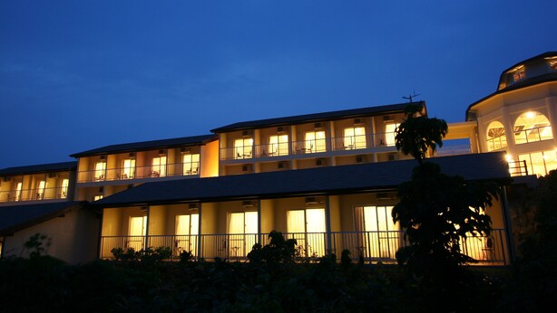 A multi-story hotel with balconies and large windows, featuring a flat roof and a curved corner section.