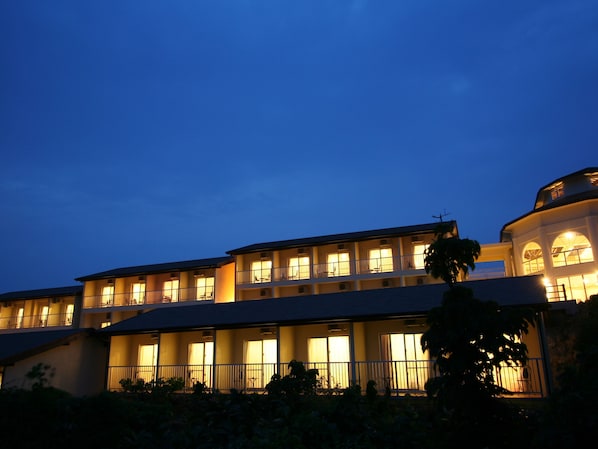 A multi-story hotel with balconies and large windows, featuring a flat roof and a curved corner section.