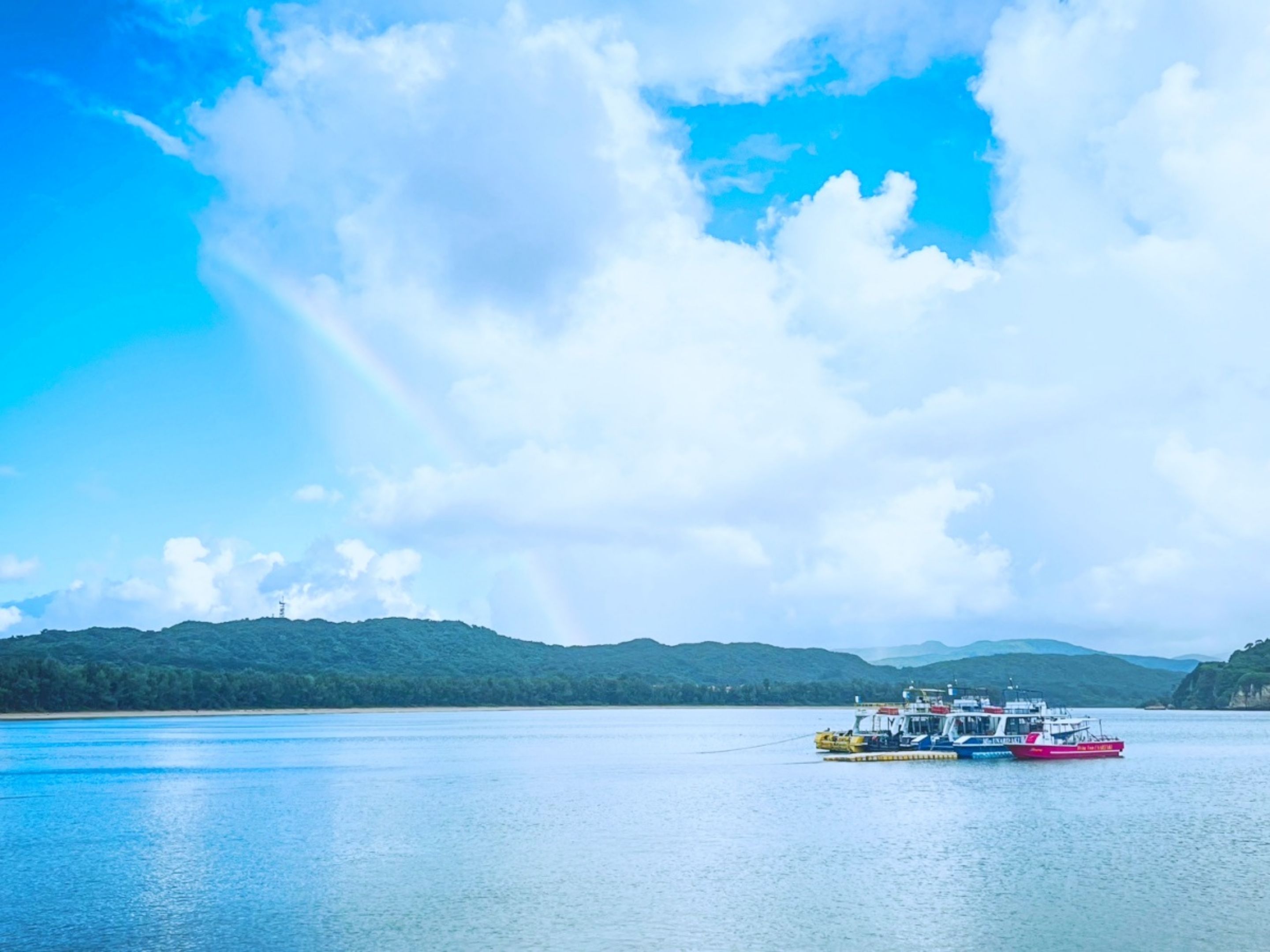 A calm lake with a boat docked on the shore, surrounded by hills.