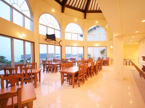 A spacious dining area with high ceilings and large windows offering views of the sea. - HOTEL ILMARE UNARIZAKI (Taketomi)