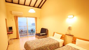 A hotel room with two beds, a desk with a computer, a chair, a balcony with a view, and a phone on the wall.