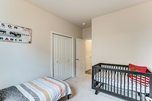 A baby room with a crib, a changing table, and a door leading to another room.