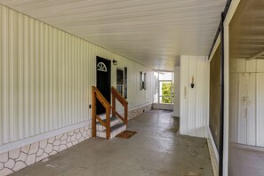 A corridor with a stone wall, wooden staircase, and a door leading to a covered area.