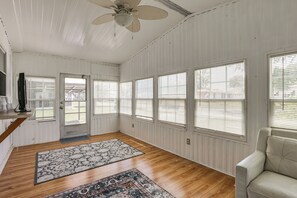A spacious room with wooden floors, large windows with blinds, a ceiling fan, and a door with a screen. - Golf, Sunshine & Fun in the Villages! (Lady Lake)