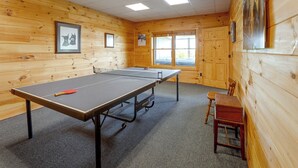A ping pong table in a room with wooden walls and a window. - Mountain Top Lodge with Amazing Vista (Jasper)