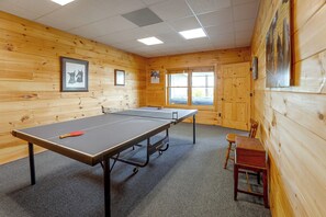 A ping pong table in a room with wooden walls and a window. - Mountain Top Lodge with Amazing Vista (Jasper)
