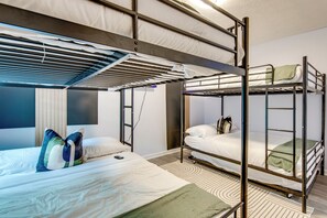 Ein Mehrbettzimmer mit Fenster, Schreibtisch und Stuhl.